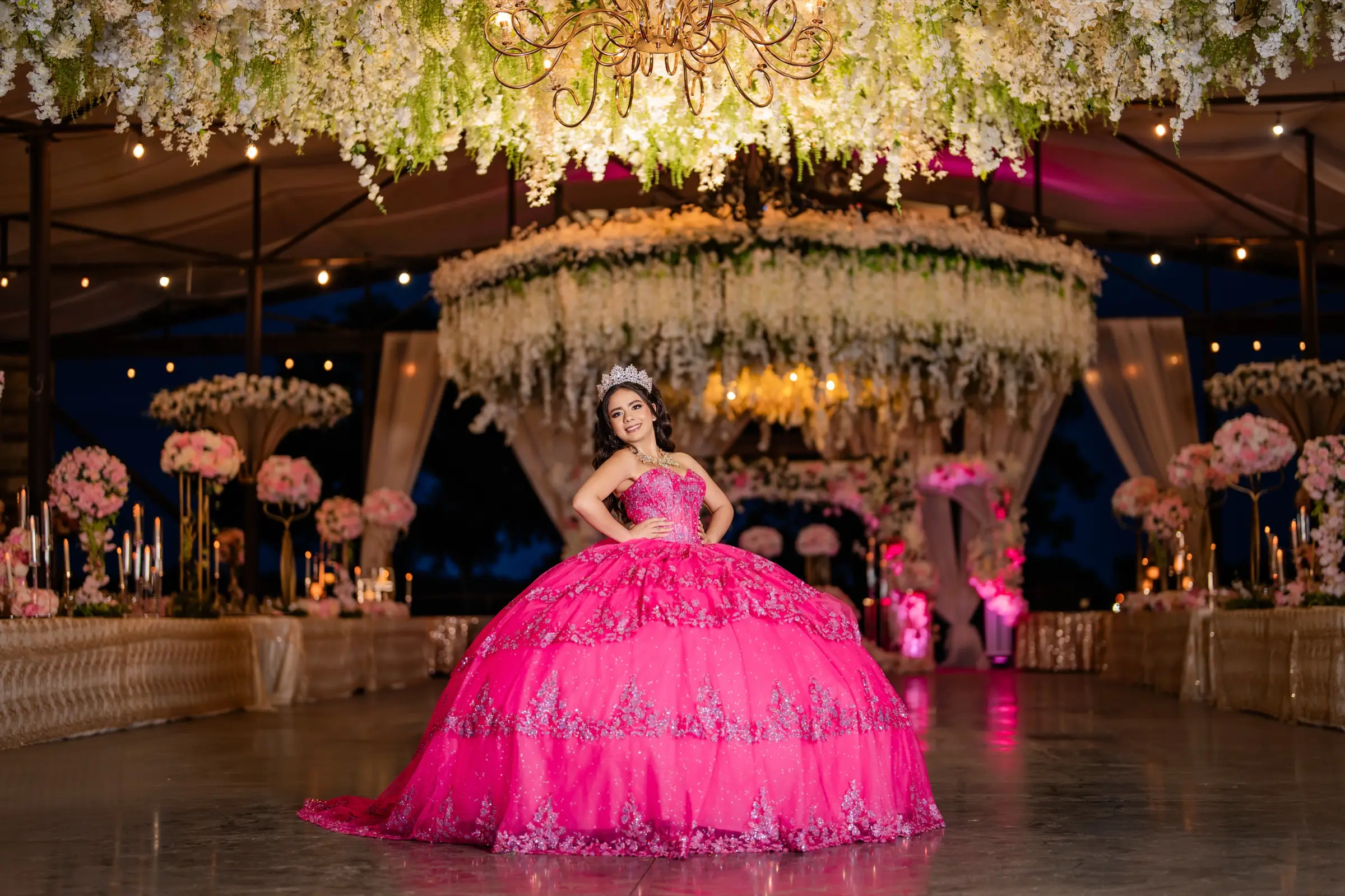 Quinceañera in a fuchsia ball gown in a ballroom