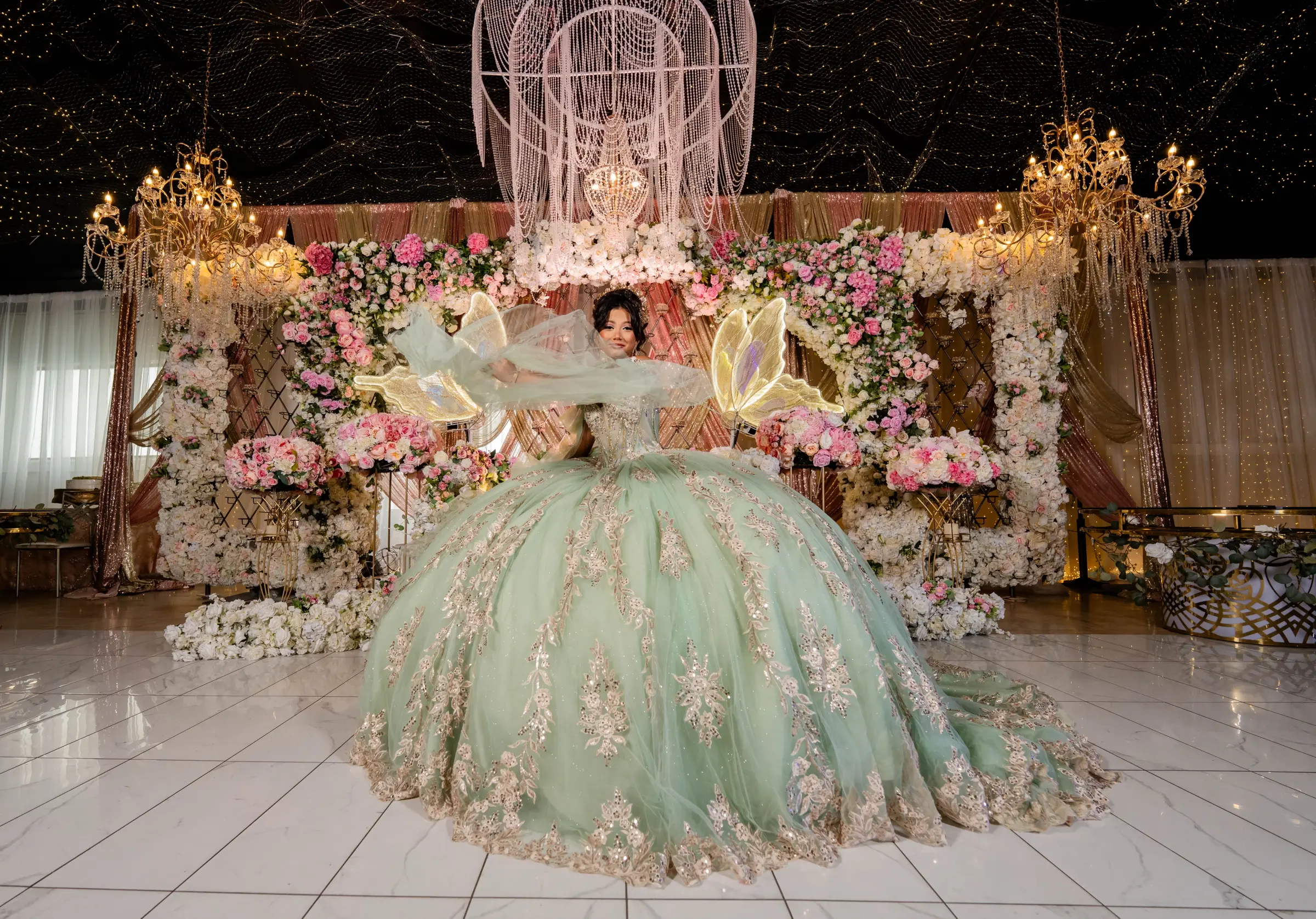 Quinceañera in a sage gown with a birdcage backdrop
